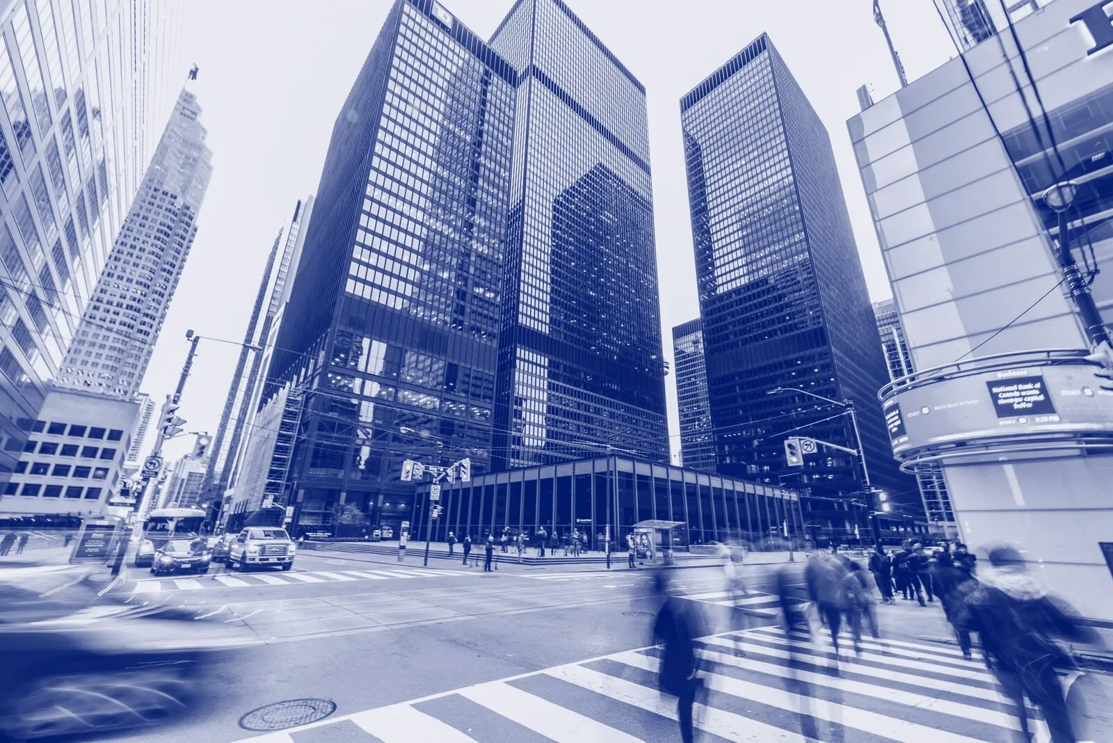 People crossing a street between office towers in a financial district