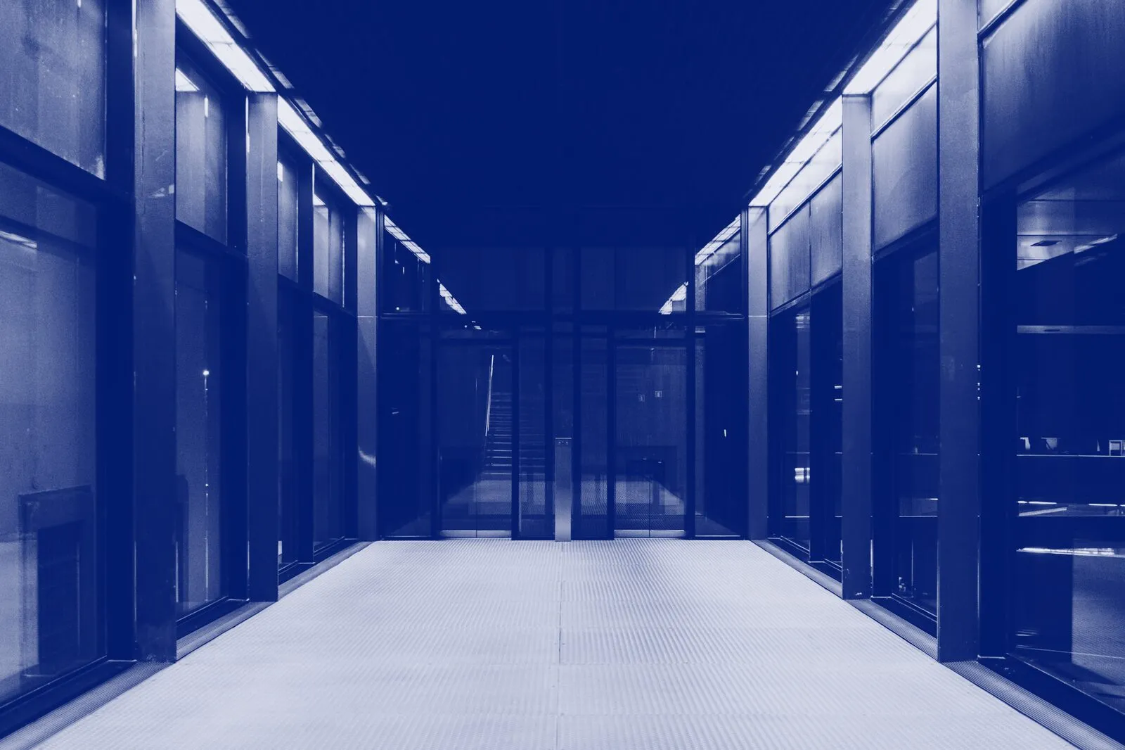 A long data-centre aisle between glass-fronted server rooms